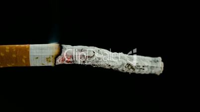 Burning cigarette on black background in reverse