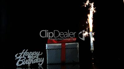 Sparkler burning beside gift and happy birthday sign
