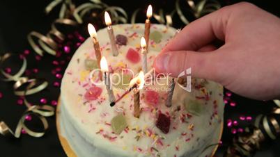 Hand lighting candles on birthday cake