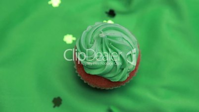 St patricks day cupcake revolving with shamrock confetti falling