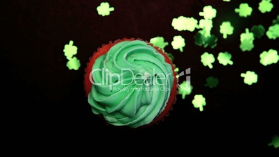 St patricks day cupcake revolving with green shamrock confetti falling