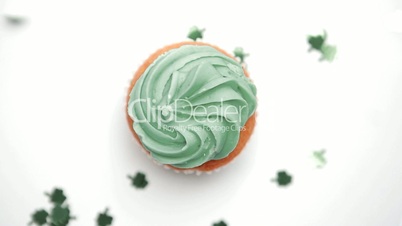 St patricks day cupcake turning with green shamrock confetti falling