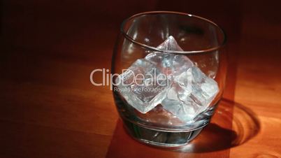 Tumbler of ice being filled with whiskey