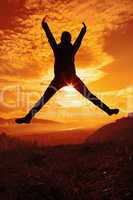 Happy young woman jumping at the sunset