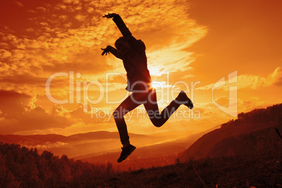 Happy young woman jumping at the sunset