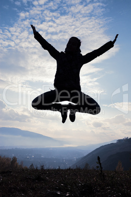 Happy young woman jumping at the sunset