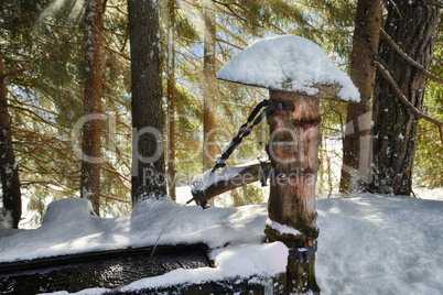 Verschneiter Brunnen aus Holz