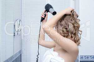 Pretty blonde woman with hairdryer in bathroom