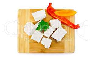 Feta cheese pieces on the board with pepper