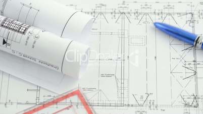A pen rolls over  an architectural drawing blueprint.