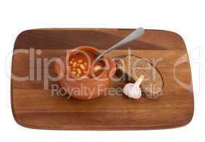 Soup in clay pot with bread and garlic on wooden kitchen board