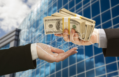 Male Handing Stack of Cash to Woman with Corporate Building
