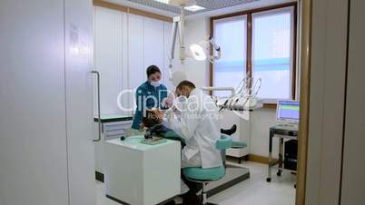 Dentist and assistant checking dental hygiene of female client