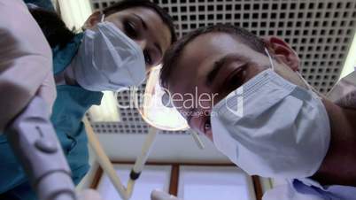 Dentist and assistant working, inspecting mouth of sick patient