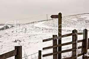 Blank wooden signpost on snow covered moorland