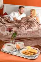 Happy couple lying bed romantic breakfast hotel