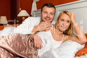 Smiling husband holding wife lying bed married