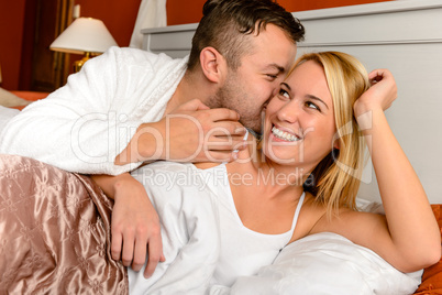Happy couple bed man giving kiss woman