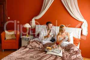 Loving couple drinking coffee hotel bedroom