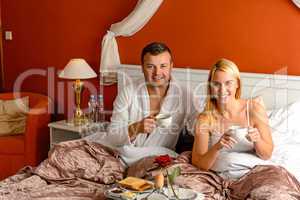 Sitting happy husband wife bed drinking tea