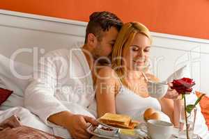 Snuggling couple romantic morning bed drinking coffee