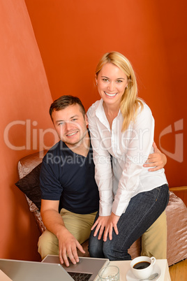 Happy couple using laptop computer sitting together