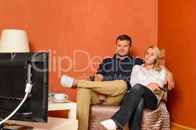 Young couple watching tv cuddling sitting armchair