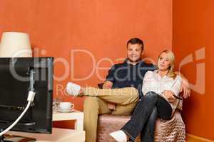 Young couple watching tv cuddling sitting armchair