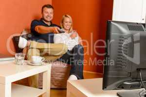 Happy couple watching tv evening changing channels