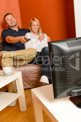 Happy couple watching television together relaxing sofa