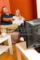Happy couple watching television together relaxing sofa