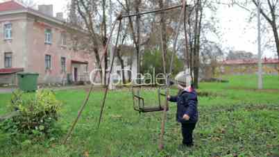 The little boy is swinging an old swing.