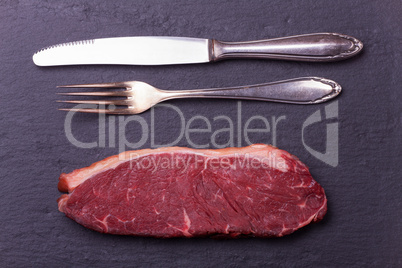 rohe Steak und Besteck auf Schiefer