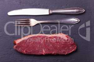 rohe Steak und Besteck auf Schiefer