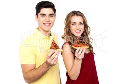 Young lovers posing with pizza slice in hand