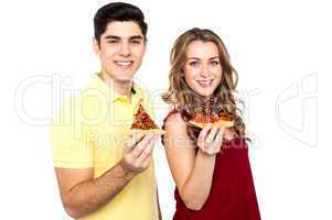 Young lovers posing with pizza slice in hand