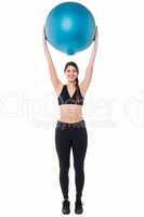 Fitness enthusiast holding ball above her head