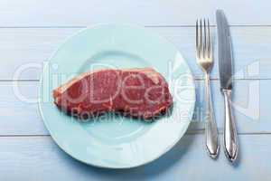 rohes Steak auf einem blauen Teller