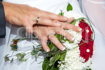 Hands with wedding rings and bridal bouquet