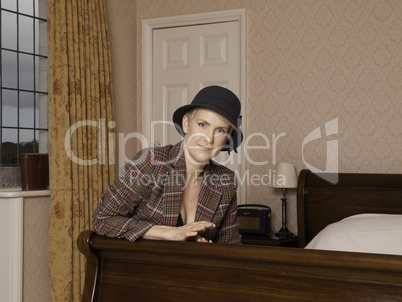 Woman in jacket, hat and lingerie on bed