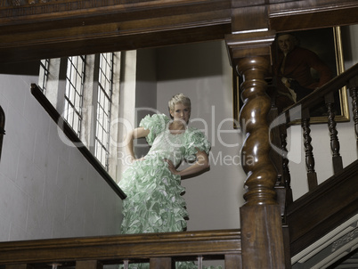 Pretty blond woman standing on stairs with green ball gown