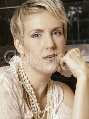 Blond woman in a camisole waering pearls