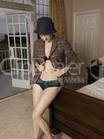 Woman in jacket, hat and lingerie by bed
