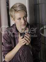 Beautiful Girl by the window waiting with a cup of tea or coffee