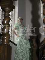 Pretty blond woman standing on stairs with green ball gown