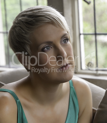 Beautiful Blond Girl in green dress by window