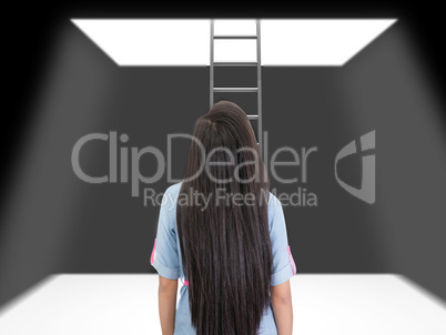 woman standing in a pit looking up to the ladder that leads out