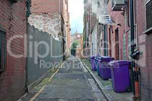 Rubbish bins lined up in narrow cobblestoned alley