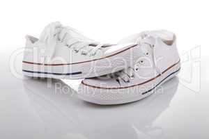 Pair of new white sneakers on white background with reflection