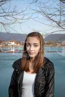 Teenage girl in black leather jacket by the lake